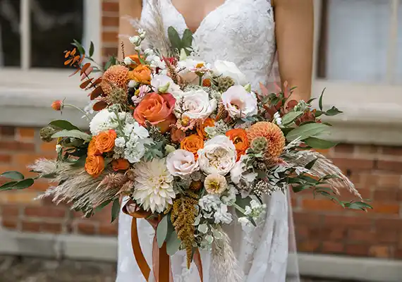 Woman in wedding dress holding fall themed flower bouquet