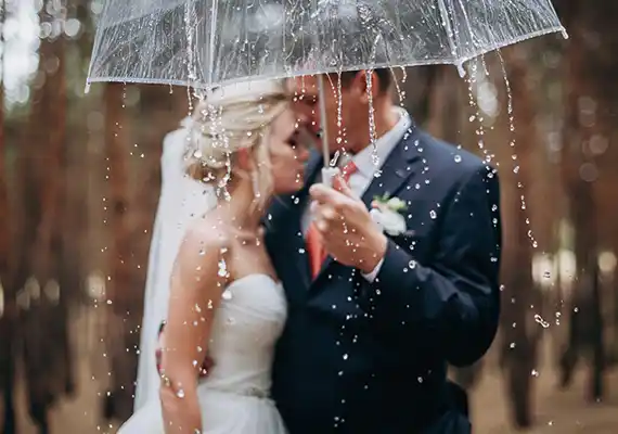 Bride and groom holding an umbrella in the rain